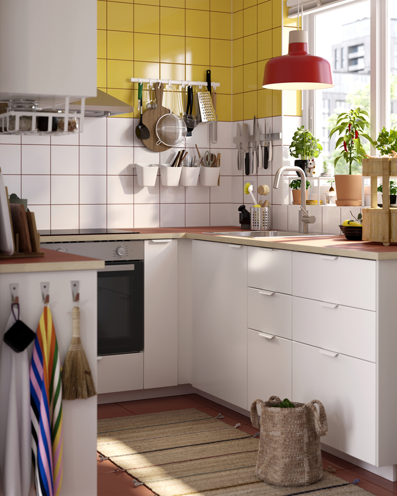 Cocina compacta y luminosa con muebles blancos, azulejos amarillos y detalles funcionales, ideal para espacios pequeños y bien organizados.