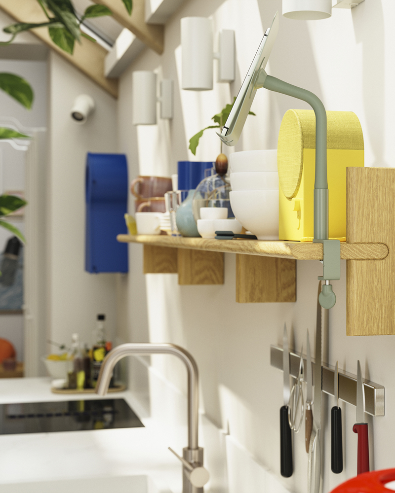 En la pared de la cocina se monta un estante de pared KLAVRESTRÖM de roble macizo y sobre él se coloca un altavoz Bluetooth NATTBAD.
