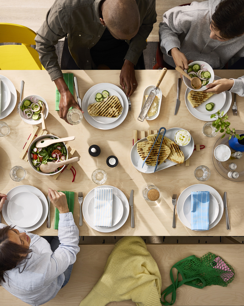 Vista aérea de una mesa BERGSHYTTAN en chapa de abedul donde la gente comparte una comida en platos blancos GODMIDDAG.
