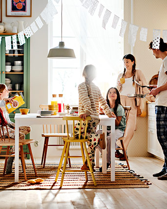 Grupo en mesa decorada con ambiente festivo y luz natural. Comida y bebida sobre la mesa.