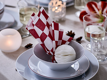 Detail of Christmas table, with white tableware and red checked napkins decorating it.