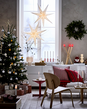 Christmas living room with decorated tree, star-shaped lamps in the window and red details in the textiles