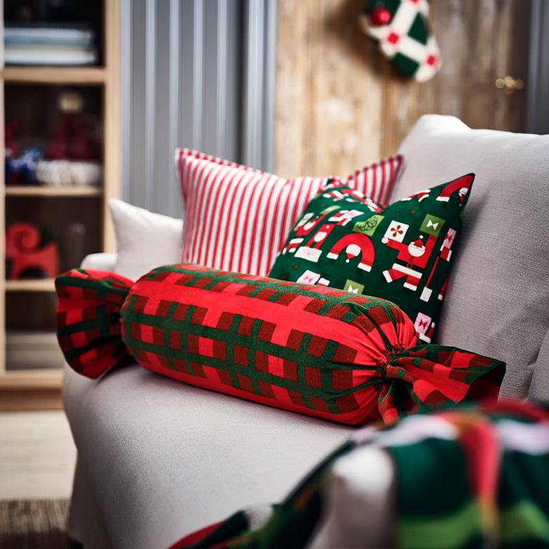 Red and green cushions with Christmas motifs on a grey sofa