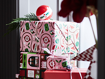 Gifts wrapped in red patterned paper and decorated with Christmas tree baubles