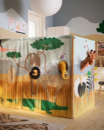 Detalle de la estructura de juego de madera, con paneles de tela estampados con animales de safari y aberturas circulares para jugar con peluches.