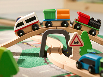 Wooden toy train set with colorful cargo cars crossing a bridge on wooden tracks. Perfect for developing motor skills and imagination during playtime