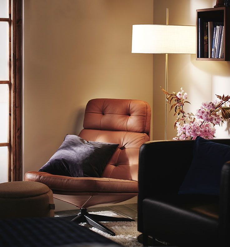 Rincón relajante en un dormitorio con sillones HAVBERG y EKERÖ, una mesa auxiliar, flores, una lámpara de pie y un reloj de pared.