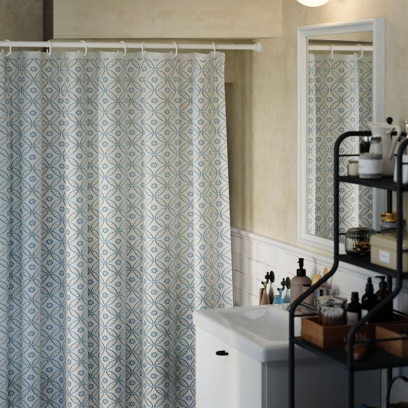 Una barra para cortina de ducha BOTAREN en color blanco se coloca bajo una escalera en un aseo pequeño, con una cortina que oculta las estanterías.