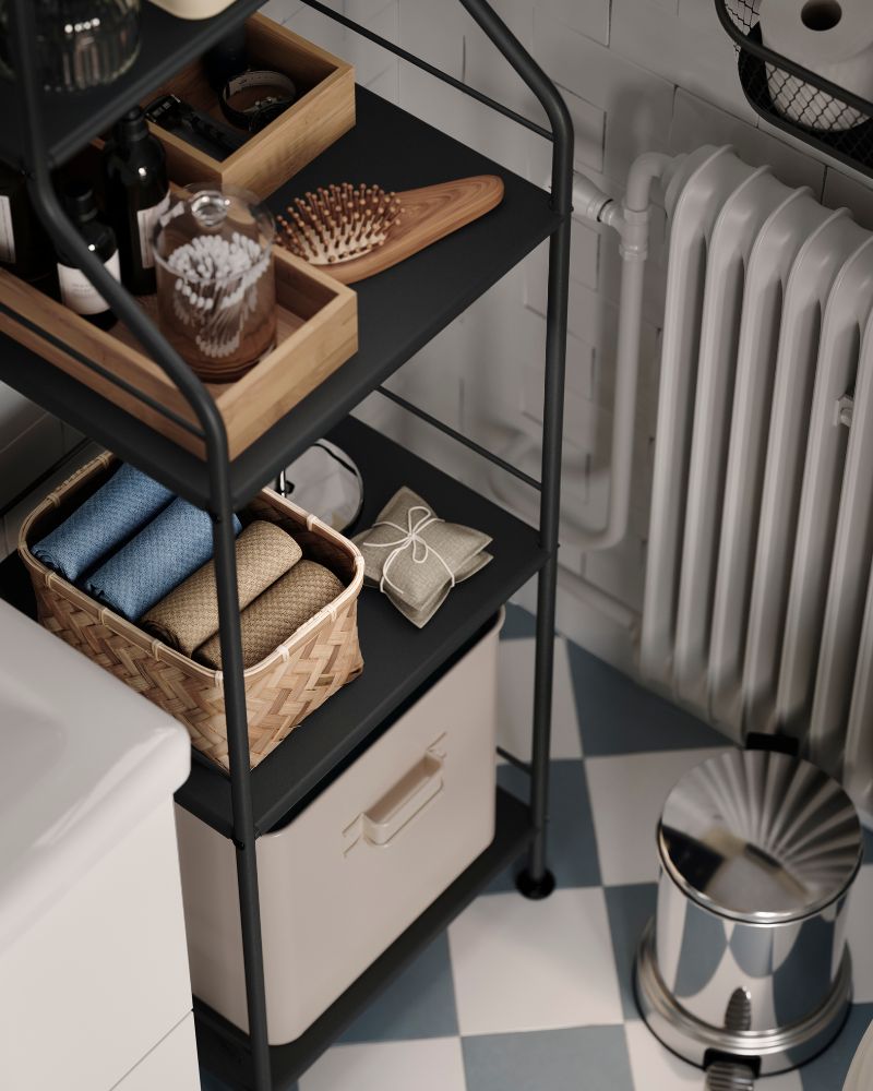 Claro, aquí tienes la traducción al español:  Una vista aérea de la parte inferior de una estantería de baño, con una cesta MJÖLKKANNA de bambú trenzado que contiene toallas dobladas.