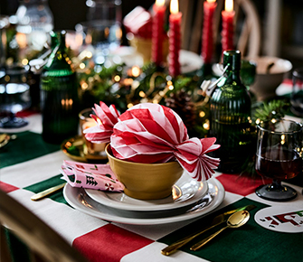 Mesa navideña con cuenco a rayas rojas y blancas, velas encendidas y decoraciones festivas para crear un ambiente acogedor