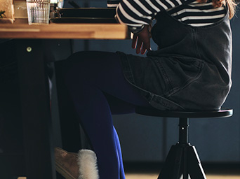 Una niña sentada en un banco y apoyada en la mesa