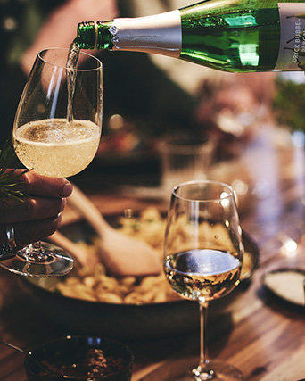 dos copas de cristal siendo rellenadas por una botella de gaseosa