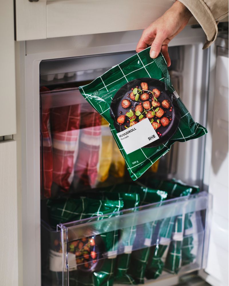 A hand pulls a bag of HUVUDROLL plant balls out of freezer.