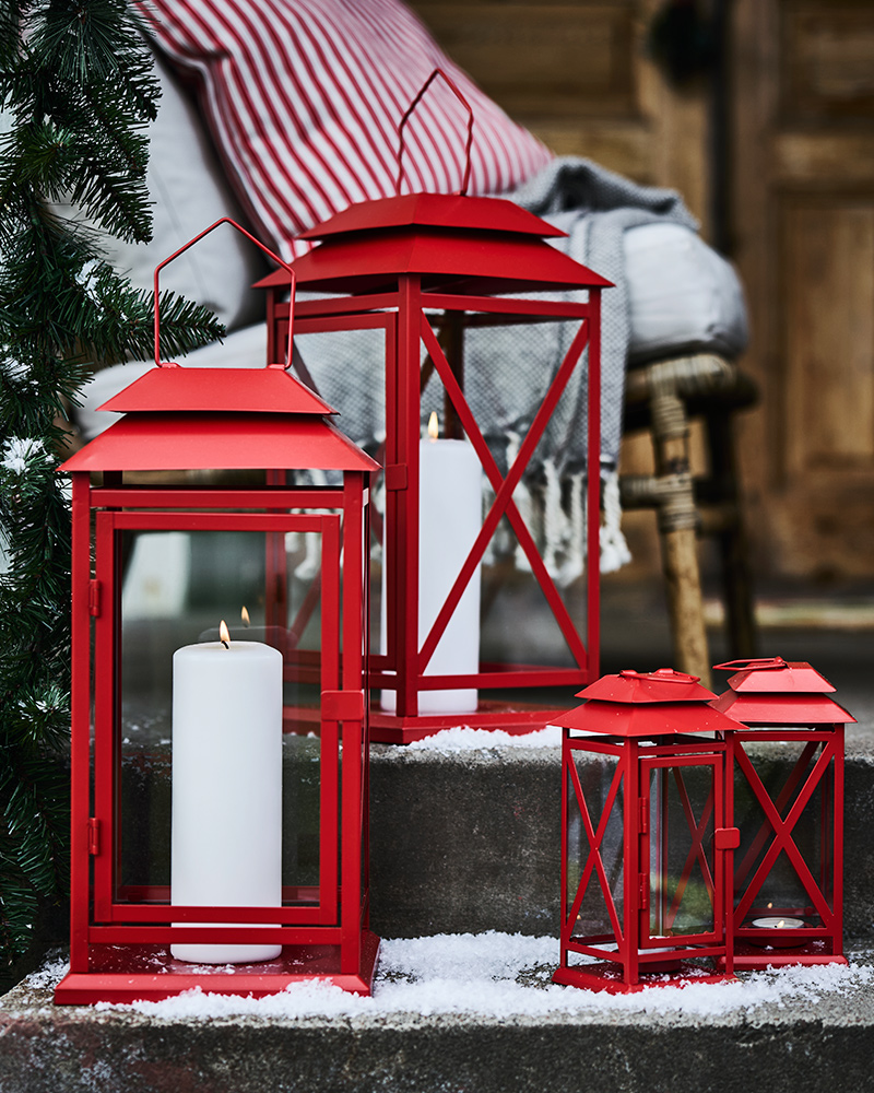 Faroles VINTERFINT rojos grandes y pequeños con velas FENOMEN en un porche.