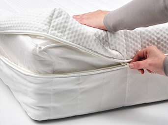 Hands opening a white mattress protector with zipper closure. Protects your mattress from spills and wear