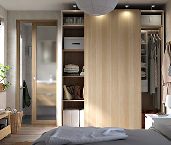 Armario modular de color roble claro PAX con puertas correderas y estantes abiertos. Dormitorio con puerta de vidrio esmerilado.