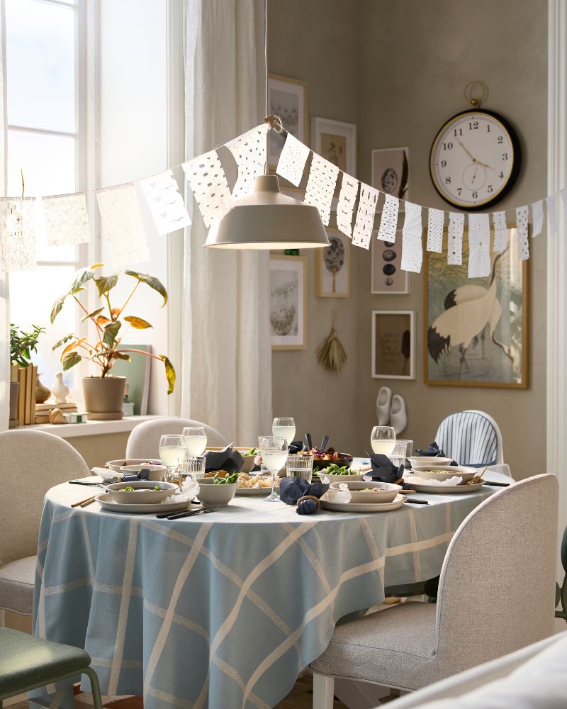 Un comedor luminoso tiene una mesa extensible ROSENTORP que ha sido ampliada para acomodar cinco sillas y una silla alta.