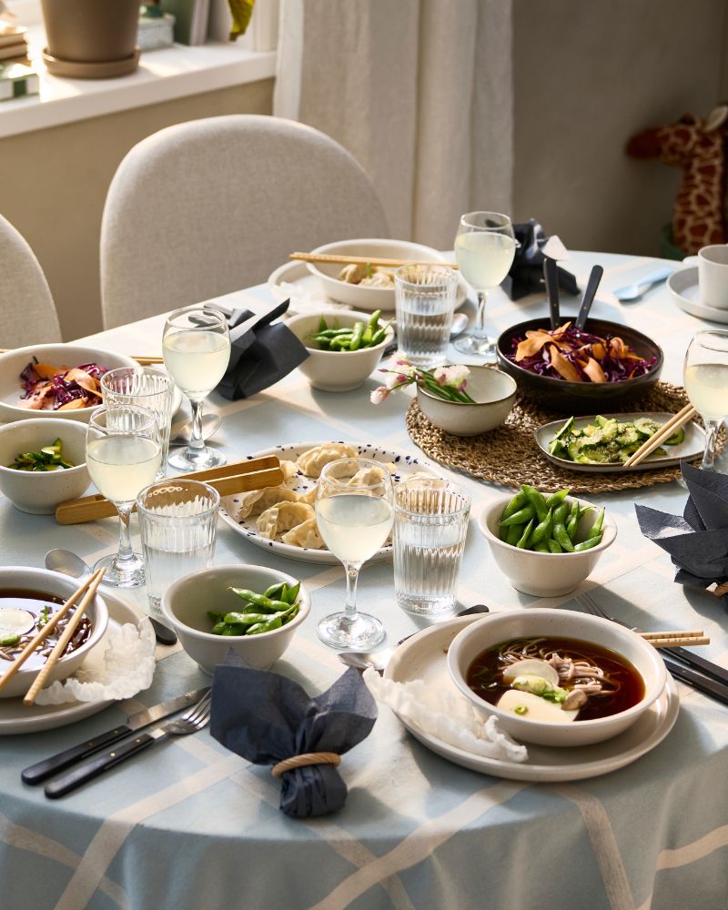 Una mesa extensible ROSENTORP ha sido preparada para una comida festiva, con sopa servida en cuencos y empanaditas colocadas en una bandeja para servir.