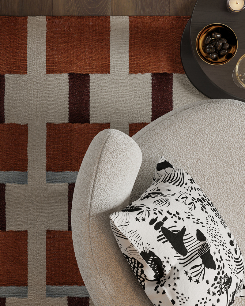  Un cojín con funda STOCKHOLM 2025 reposa sobre un sillón STOCKHOLM 2025 sobre una alfombra STOCKHOLM 2025.