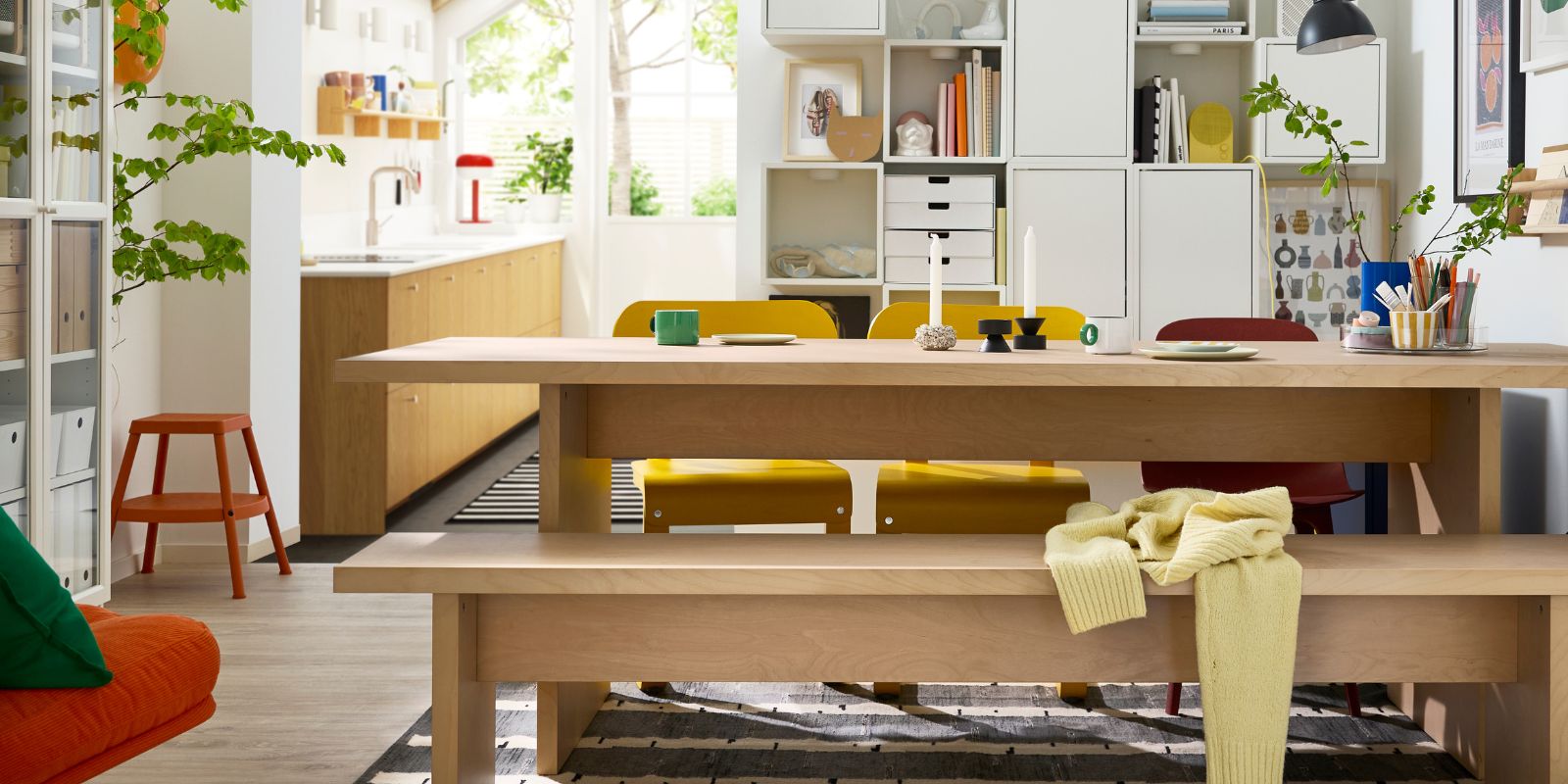 A bright dining room has a BERGSHYTTAN table with a bench in birch veneer on one side and colourful chairs on the other.
