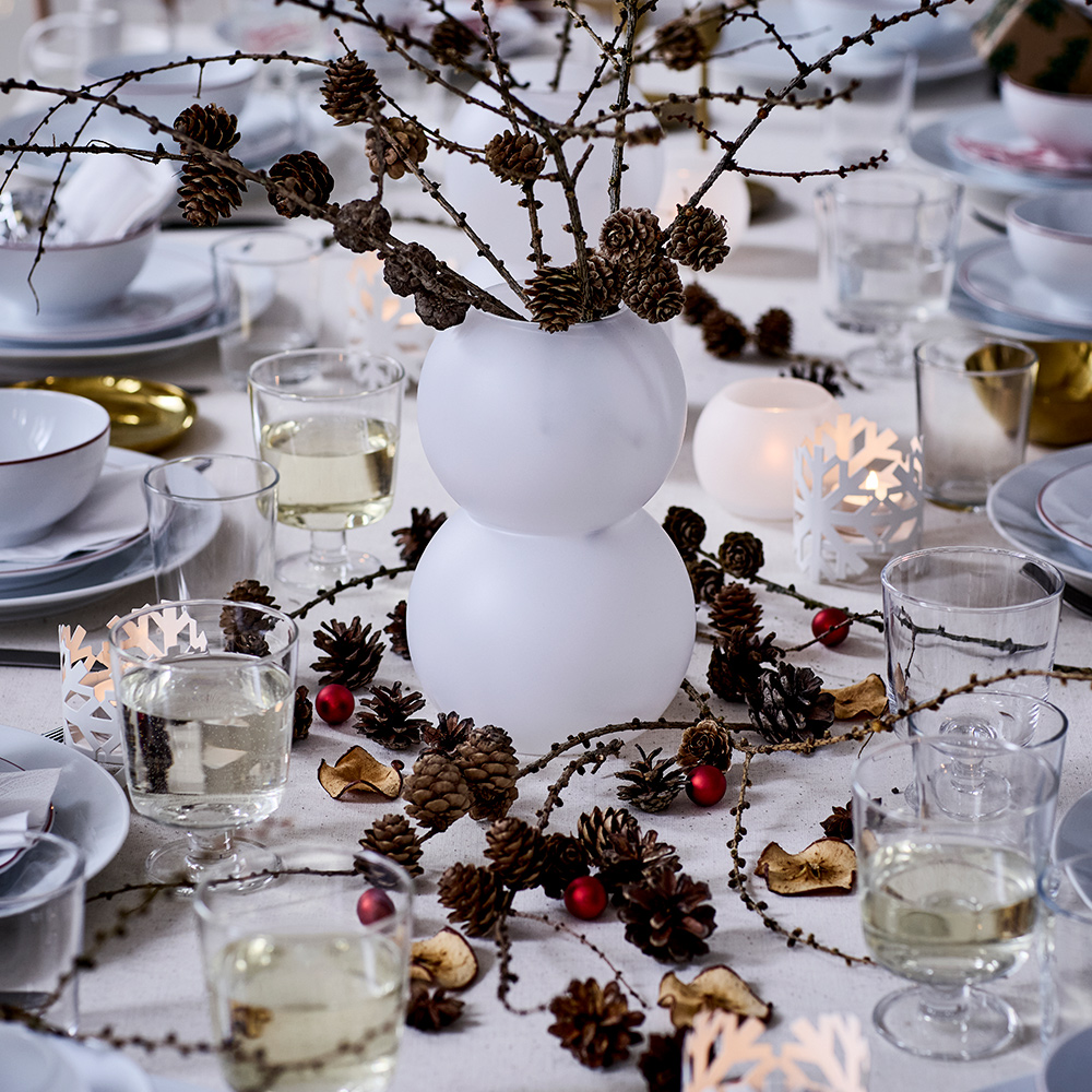 Christmas table with a vase, candle holders, bowls, and VINTERFINT charger plates.