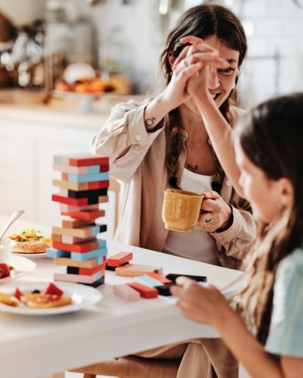 A mother and son high-five each other after successfully completing a block stacking game at the breakfast table.