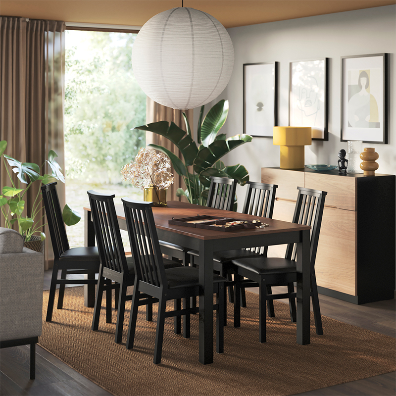 A dining area has a beige/brown ÅLHULT extendable table with a bench on one side and two chairs with soft seats on the other.