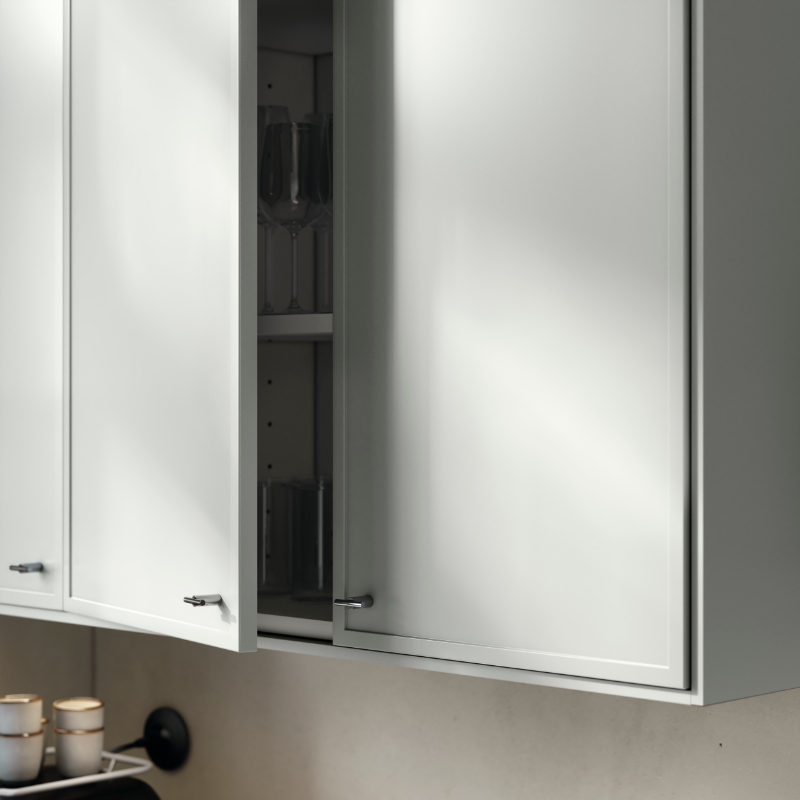 A kitchen cabinet with ASPUDDEN doors in light-grey, one slightly open, revealing drinking glasses and wine glasses inside.