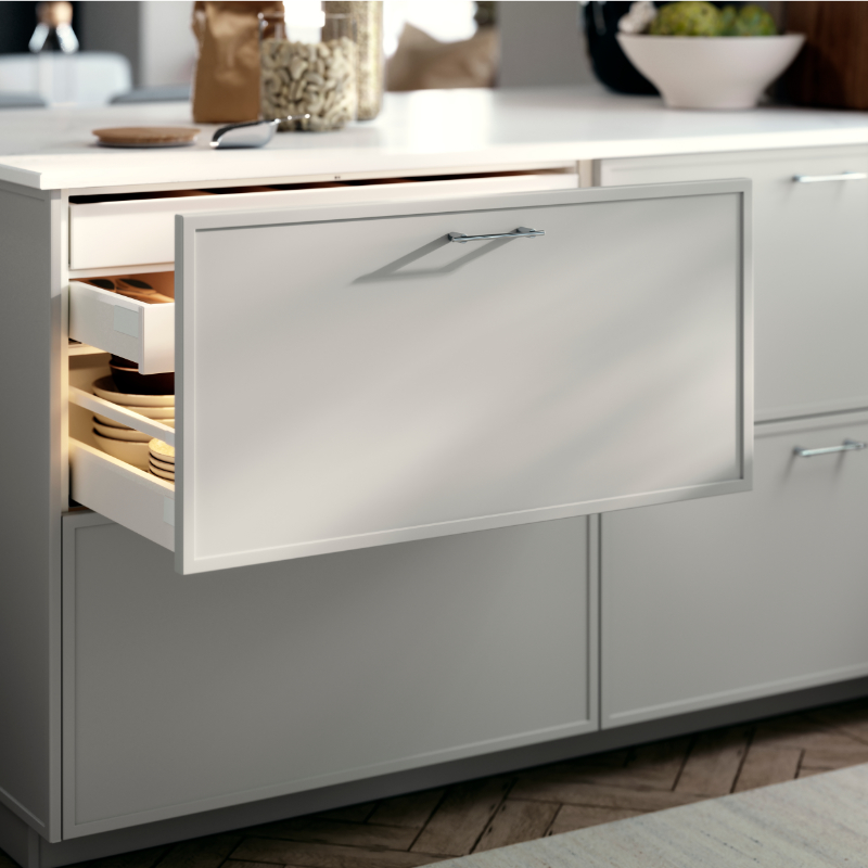METOD kitchen drawer with an ASPUDDEN drawers front in light grey, shown open with plates and bowls inside.