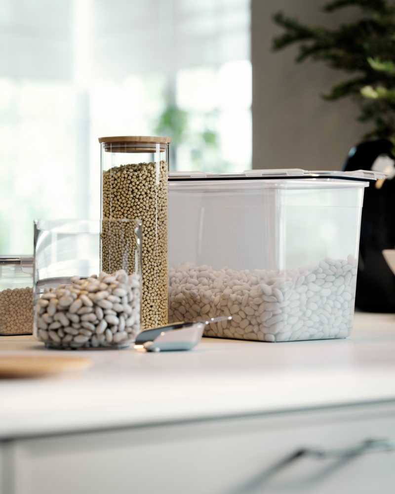 EKLATANT jar with lid filled with beans on a kitchen worktop, placed next to other clear food storage containers.