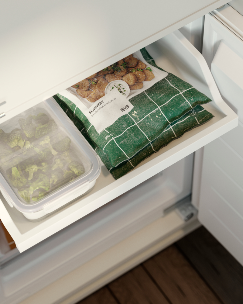 IKEA 365+ food container with vegetables stored in a freezer drawer next to frozen food packages.