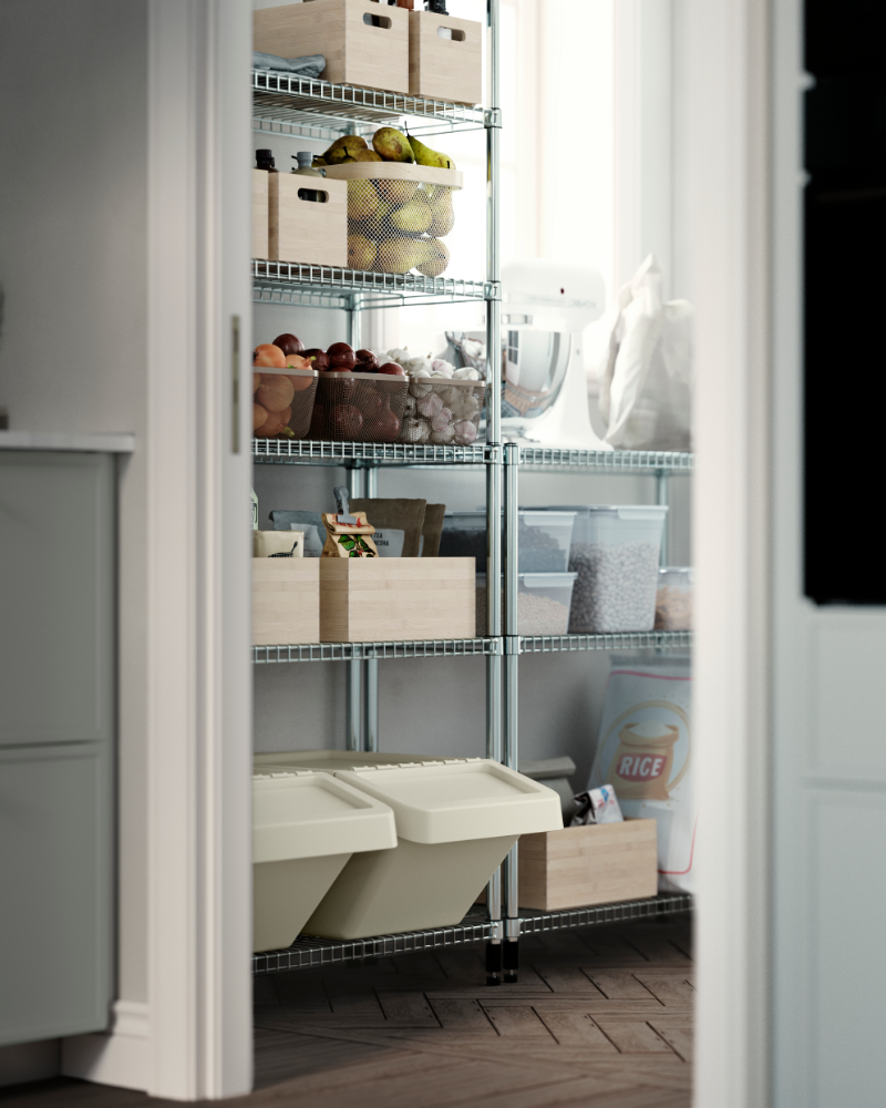 A pantry with OMAR shelving units, storing wooden boxes, glass jars, fruit baskets, dry food and a white kitchen mixer.
