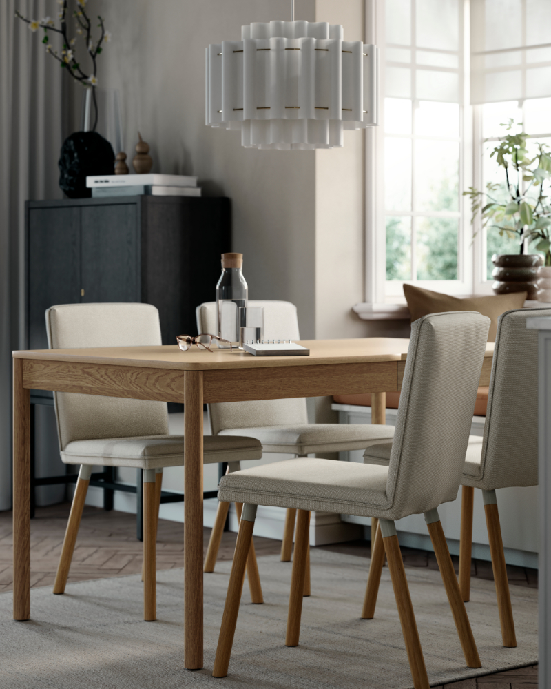 A TONSTAD extendable table in oak veneer set in a dining room with four grey chairs and natural light from windows