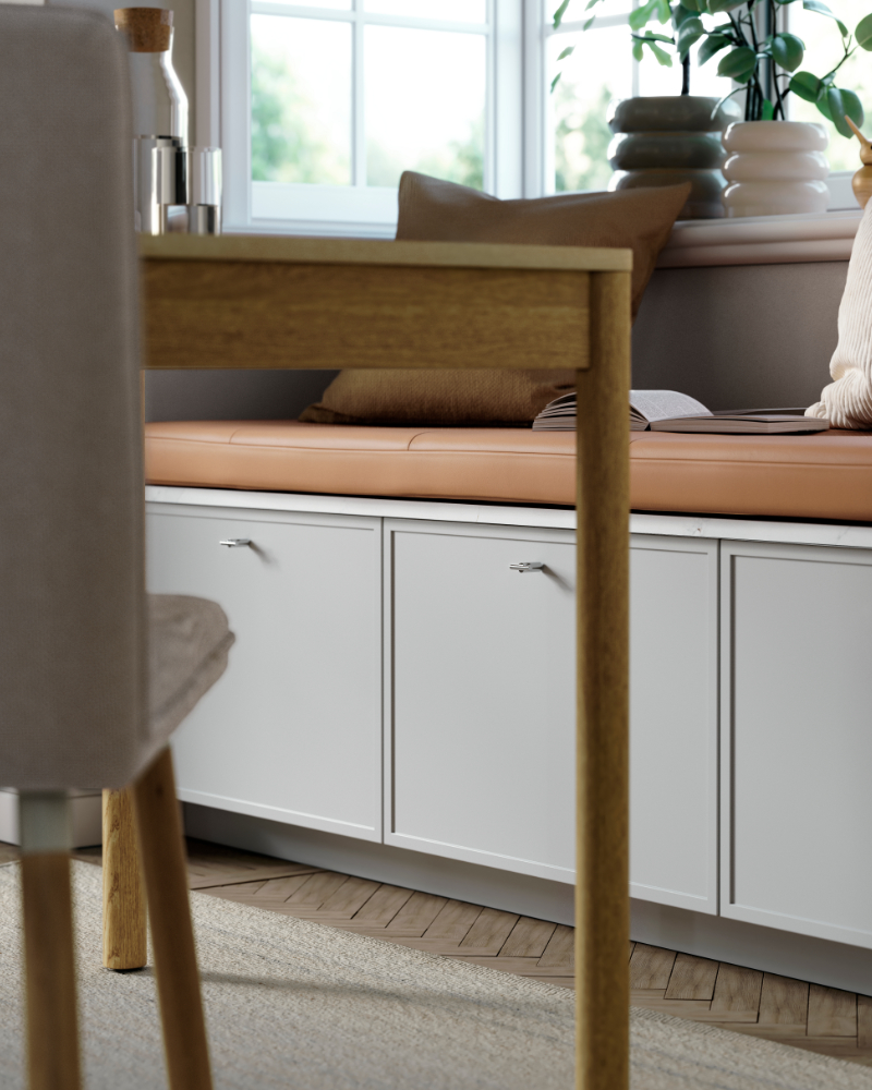 Bench seating with ASPUDDEN drawer fronts in light grey below, topped with a leather seat and decorative cushions.