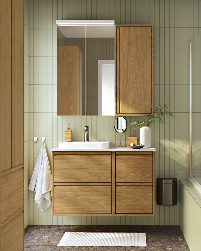 Mano levantando un especiero de madera con tarros de especias, aceite y perejil fresco sobre encimera de cocina.