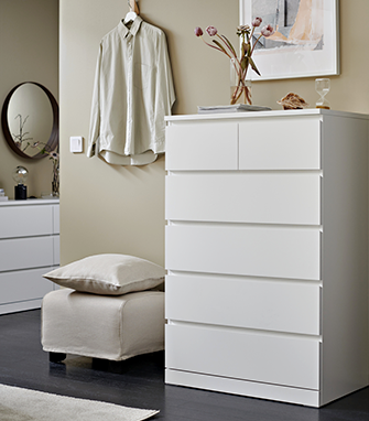Simple white chest of drawers in a bright bedroom styled with fresh flowers and natural textiles.