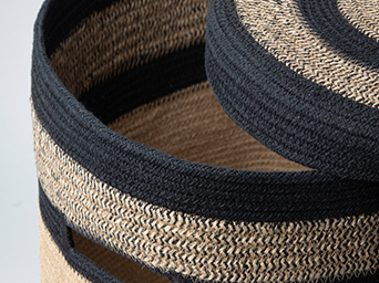 A needle with white thread inserted into a pink and orange striped cotton fabric.