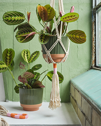 Two bell-shaped pendant lamps with woven natural fiber shades, in an industrial-style interior.