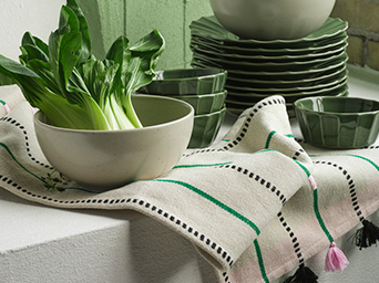 Close-up of two wool pom-poms, one pink and one orange, tied to a woven fiber basket.