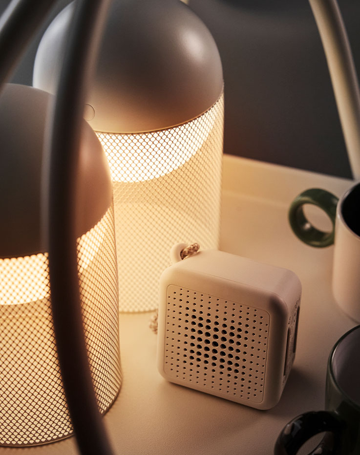 Primer plano de la iluminación decorativa LED SOLVINDEN blanca con diseño de malla y globo alimentado por pilas sobre una mesa.