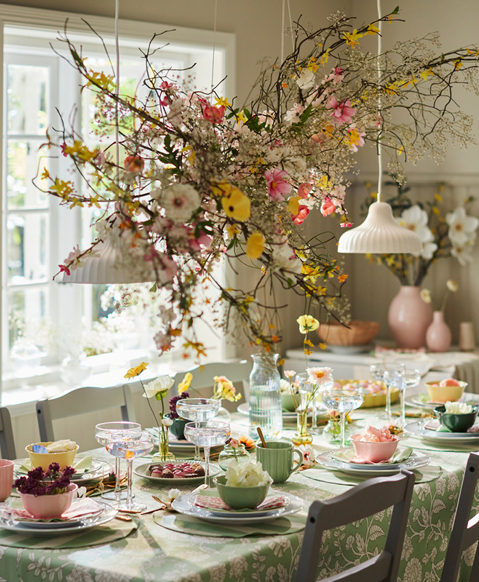 A table decorated with floral motifs, a green tablecloth and matching plates.