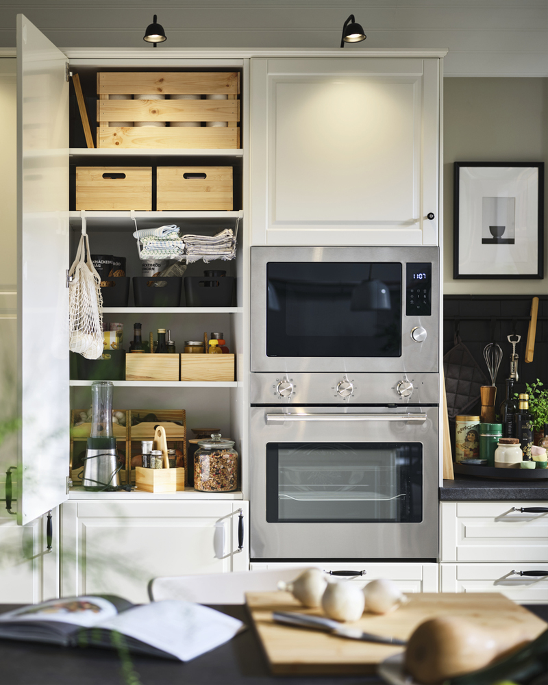 Una cocina moderna con horno y microondas de acero inoxidable junto a un armario perfectamente organizado con cajas de almacenamiento CHOKLADHAJ.