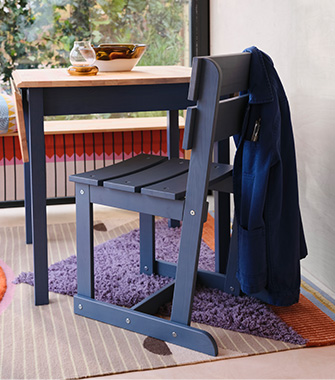 Un carnero de madera pintado de rojo brillante. Está sobre una estantería junto a un bote de galletas, piñas y rodajas de naranja secas.