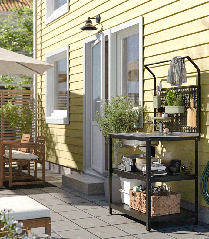 Solid wood kitchen trolley with wheels, styled as a prep station with fresh vegetables, herbs, and wooden crates on a black and white tiled floor.