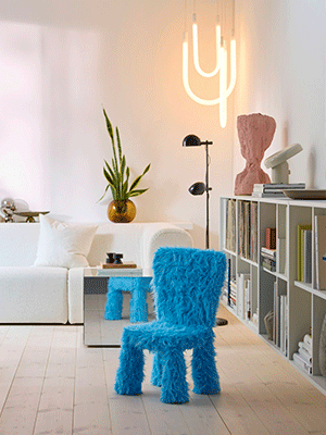 Creative living room featuring a bright blue shaggy chair, a mirrored side table, and a minimalist U-shaped neon ceiling light.