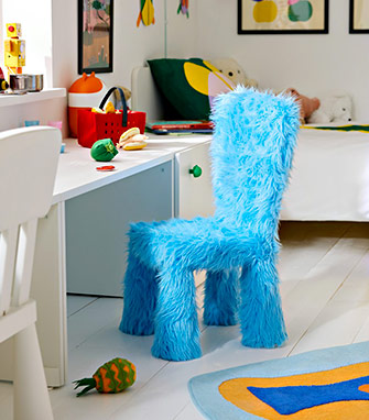 Silla infantil lúdica tapizada con pelo sintético suave de color azul brillante, situada en un dormitorio infantil luminoso y colorido.