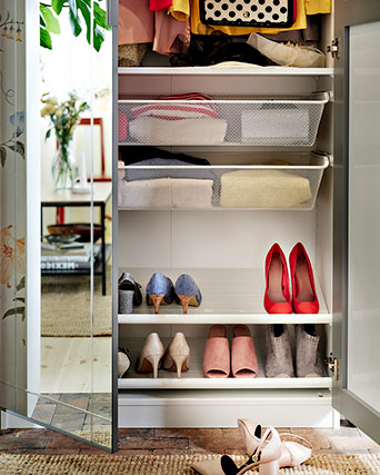 Interior de un armario blanco con cestas de rejilla para ropa y estantes inferiores organizados con varios pares de zapatos.
