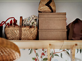 Detalle de estante de madera con cestas de mimbre y cajas de almacenaje marrones, resaltando una organización natural y clara.