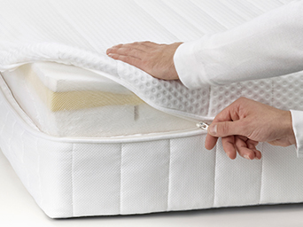 Hands opening a white mattress protector with zipper closure. Protects your mattress from spills and wear