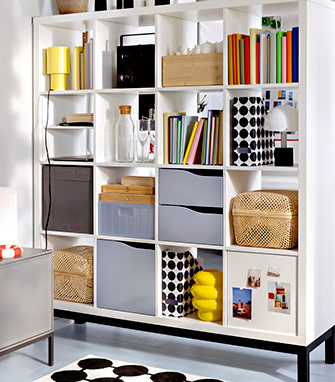 Estantería de cubos blanca con libros, cajas de almacenaje, cestas de mimbre y objetos decorativos en tonos vivos.